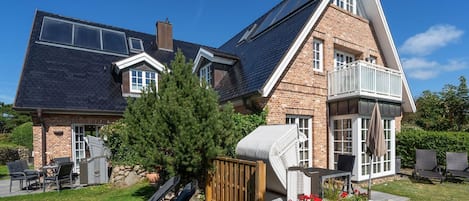 Une maison à deux étages, dotée d’un toit en pente, d’une façade en briques et d’un balcon.