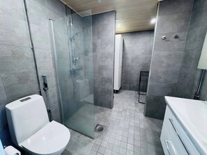 Un baño moderno con ducha de mampara de vidrio, un inodoro y un lavabo.