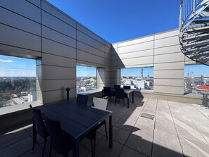 Eine moderne Außenterrasse mit Panoramablick auf die Stadt, inklusive Essbereich mit Tischen und Stühlen.