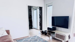 A modern living room with a flat-screen TV, a coffee table, a sofa, and a patterned rug. - Nordic Home Bliss with Sports (Helsinki)