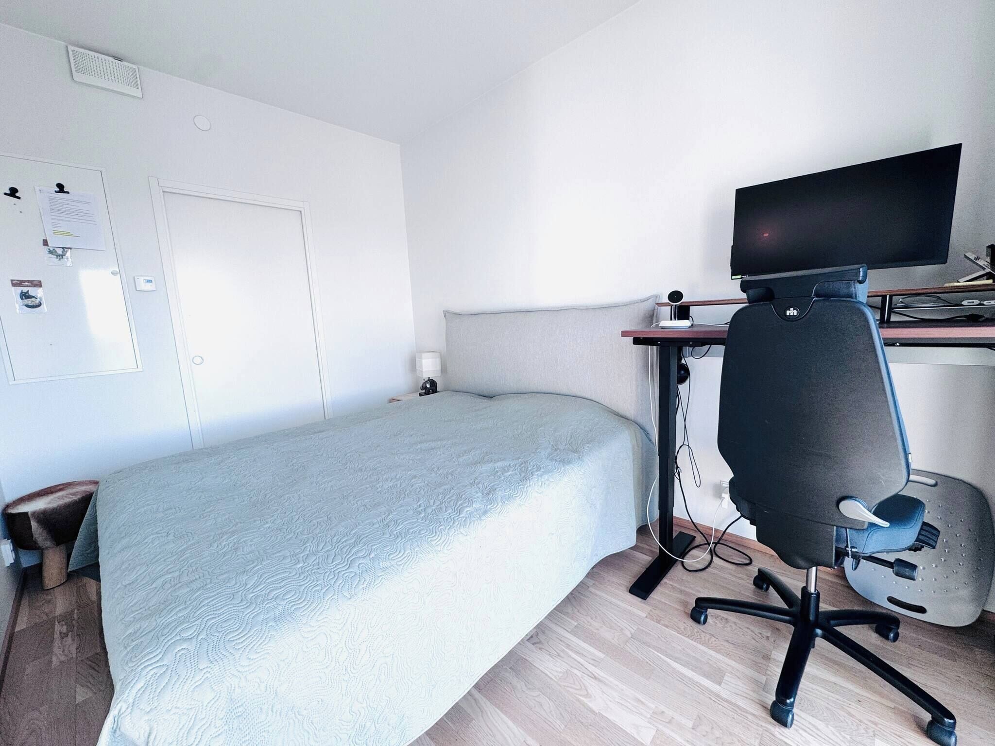A hotel room with a bed, a desk with a computer, and a chair.