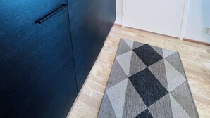 A room with a dark-colored wardrobe, a white door, and a patterned rug on the floor. - Nordic Home Bliss with Sports (Helsinki)