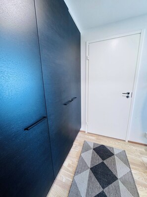 Ein Zimmer mit einem dunkelbraunen Wandschrank, einer weißen Tür und einem gemusterten Teppich.