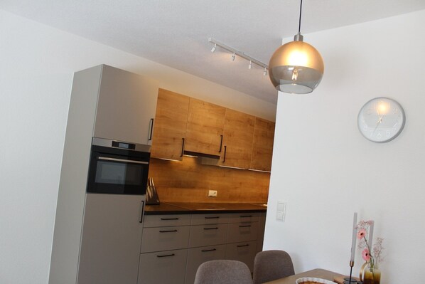 A compact kitchen with a built-in oven, wooden cabinets, and a pendant light.