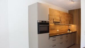 Eine moderne Küche mit Einbauofen, Spüle und Holzschränken.