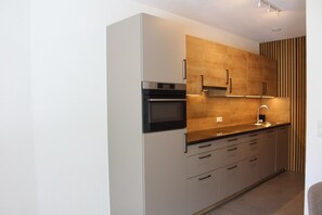 Una cocina moderna con horno empotrado, un lavamanos y armarios de madera.