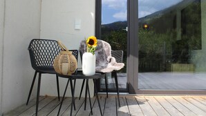 Ein Stuhl mit einem gewobenen Korb und einer Vase mit einer Sonnenblume auf einem Balkon.