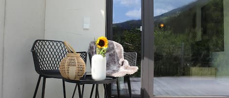 A chair with a woven basket and a vase with a sunflower on a balcony.