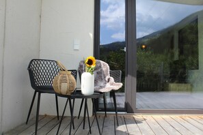 Una silla con una cesta tejida y un jarrón con un girasol en un balcón.