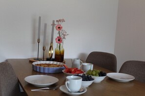 Una mesa de comedor con un frutero, un pastel y un florero con flores.
