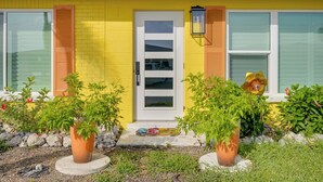A yellow house with a white door, windows with shutters, and potted plants in the front yard. - Walk to Englewood Beach! Resort-Style Villa (Englewood)