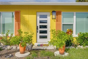 A yellow house with a white door, windows with shutters, and potted plants in the front yard. - Walk to Englewood Beach! Resort-Style Villa (Englewood)