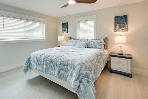 A bedroom with a bed, two bedside tables, a ceiling fan, and artwork on the walls. - Walk to Englewood Beach! Resort-Style Villa (Englewood)