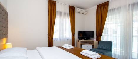 A hotel room with a bed, a desk, a television, and a chair.