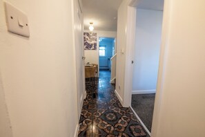 Un pasillo con baldosas de diseño, un interruptor de luz y una puerta que da a otra habitación.