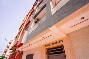 A building with a sign reading 'RESIDENCE MIRA FLORES' and a security warning sign. - Charming 2-Bedroom Apartment in the Heart of Martil, Morocco (Martil)