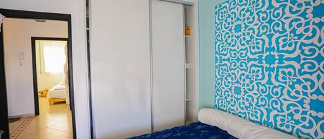 Un dormitorio con cama, armario y un panel decorativo en la pared.