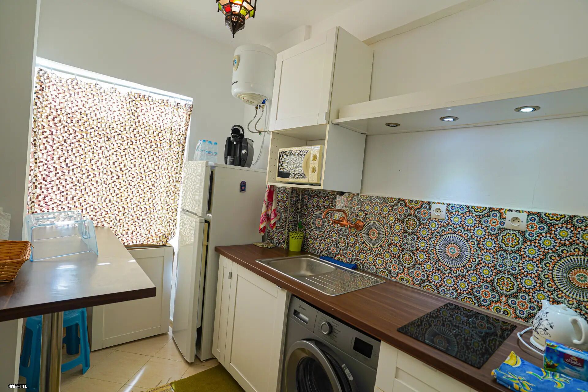 A compact kitchen with a washing machine, a microwave, and a sink.
