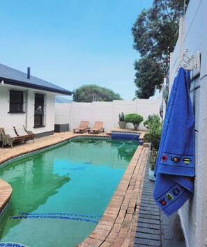 A swimming pool with a tiled edge, lounge chairs, and a bench. - Bonita Vista Plattekloof (Cape Town)