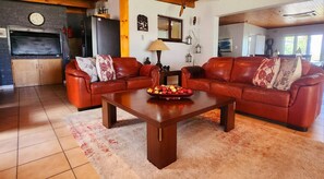 A living room with two leather sofas, a wooden coffee table, and a tiled floor. - Bonita Vista Plattekloof (Cape Town)