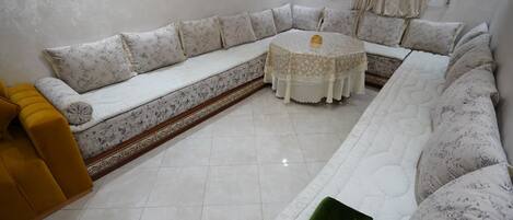 A living room with a large L-shaped sofa, a round coffee table, and a yellow armchair.