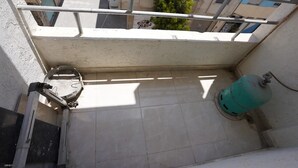 Uma varanda com guarda-corpo de metal, um cano de água e um cilindro de gás verde.