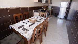 Uma cozinha compacta com mesa, cadeiras e geladeira.