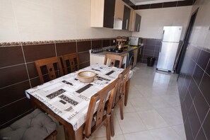 A compact kitchen with a dining table, chairs, and a refrigerator. - Charming Accessible Apartment in Martil, Morocco (Martil)