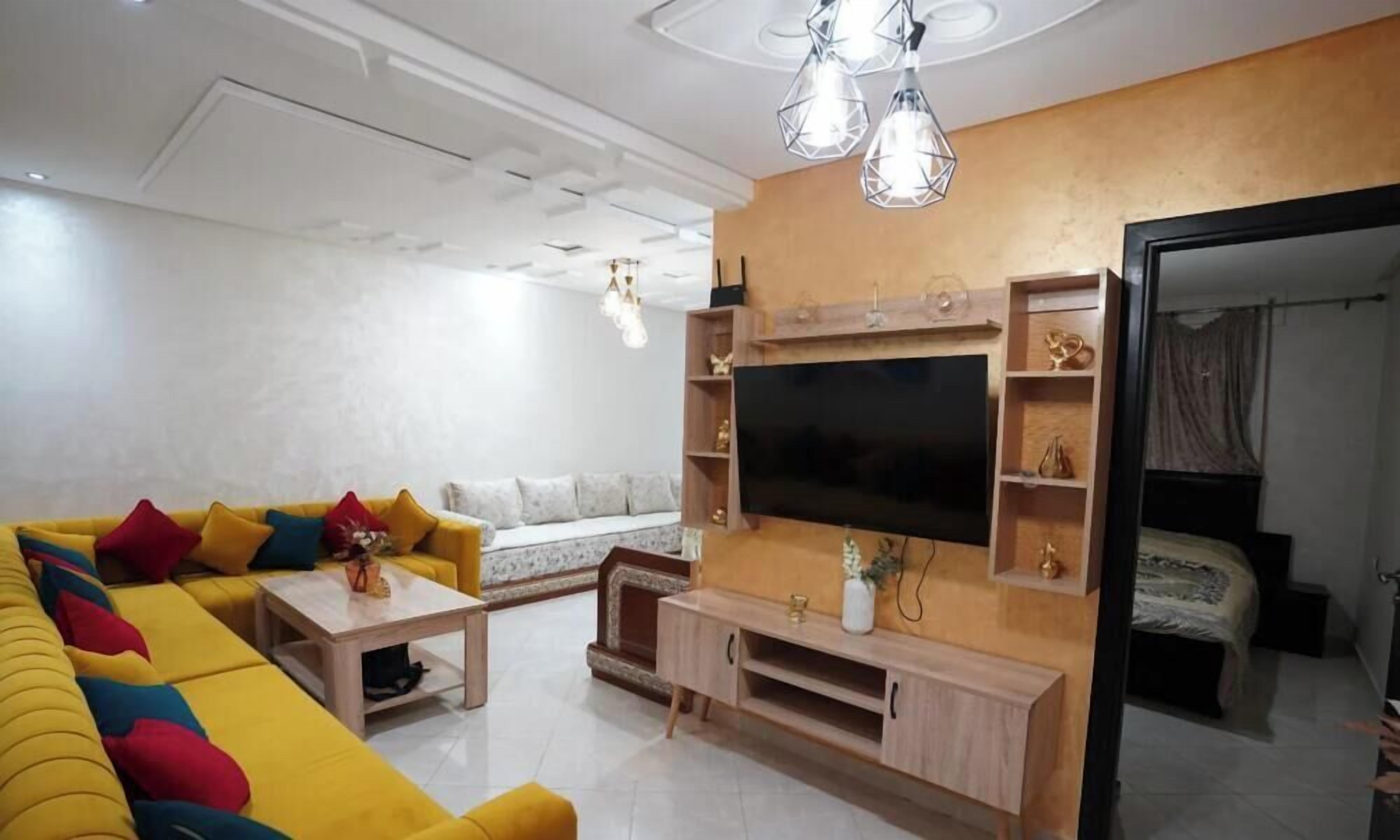 Una sala de estar moderna con un sofá amarillo, un televisor de pantalla plana y un mueble de entretenimiento de madera.
