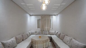Um quarto com uma mesa redonda, um sofá e uma janela com cortinas.