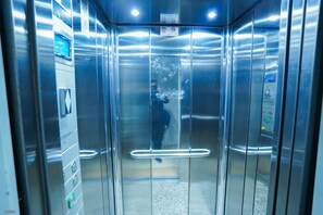 An elevator interior with metallic walls, a handrail, and a control panel on the right side. - Charming 2-Bedroom Apartment with Shared Pool in Martil (Martil)
