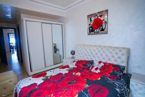 A bedroom with a large bed, a wardrobe, a mirror, and a painting on the wall. - Charming 2-Bedroom Apartment with Shared Pool in Martil (Martil)