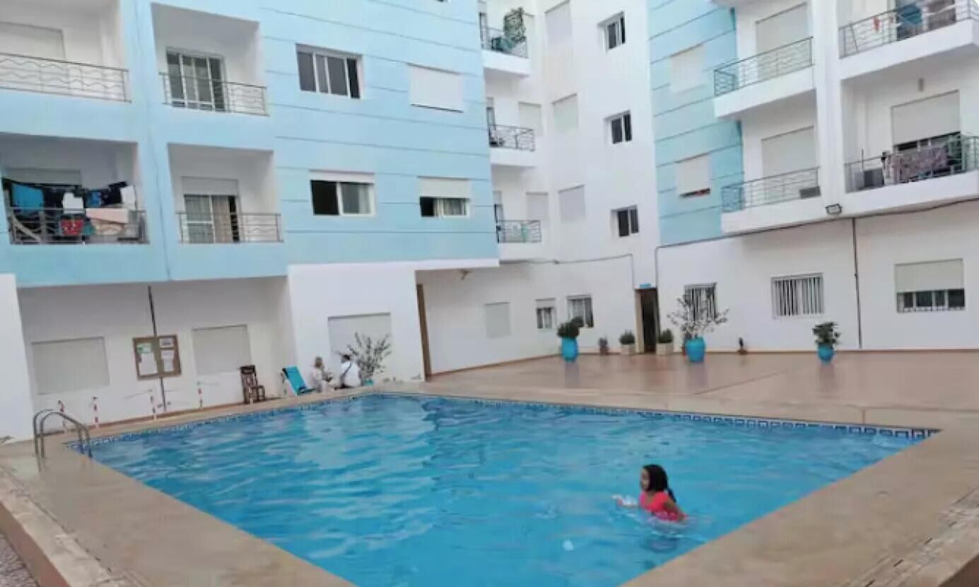 Une piscine entourée d’immeubles résidentiels à plusieurs étages, dotés de balcons.