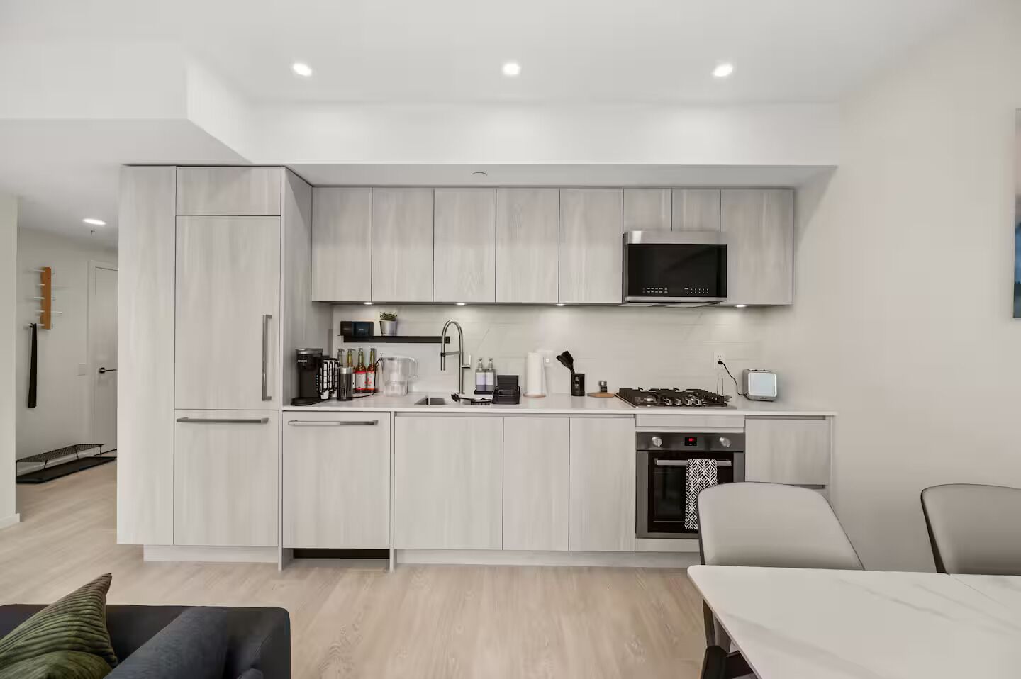 A modern kitchen with white cabinetry, a microwave, a stove, and a sink.
