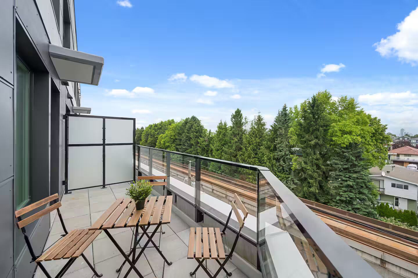A balcony with a view of a railway track, a bench, and a potted plant.