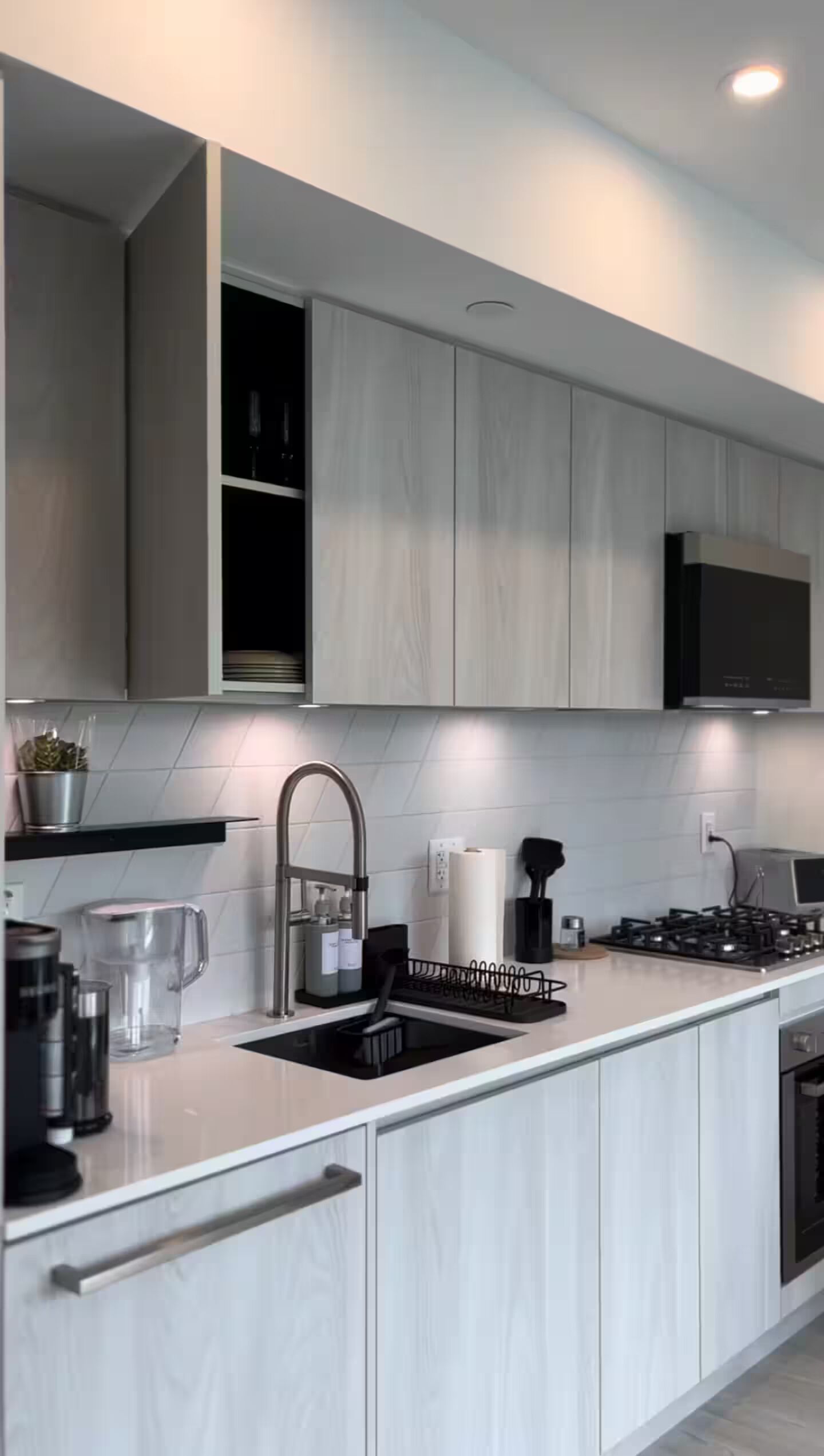 Uma cozinha moderna com máquina de lavar louça embutida, pia de aço inoxidável e exaustor.