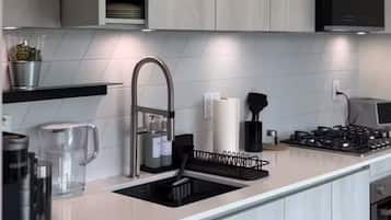 A modern kitchen with a built-in dishwasher, a stainless steel sink, and a range hood.