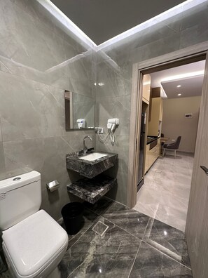 A modern bathroom with a toilet, sink, and hairdryer. - 305 AL-NAJEH JRE Apartments For Rent ave (Amman)