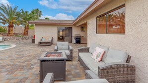 Un patio exterior techado con piscina, mobiliario de mimbre y zona de barbacoa.