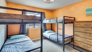 Habitación con literas, un aparador de madera y un cartel en la pared.