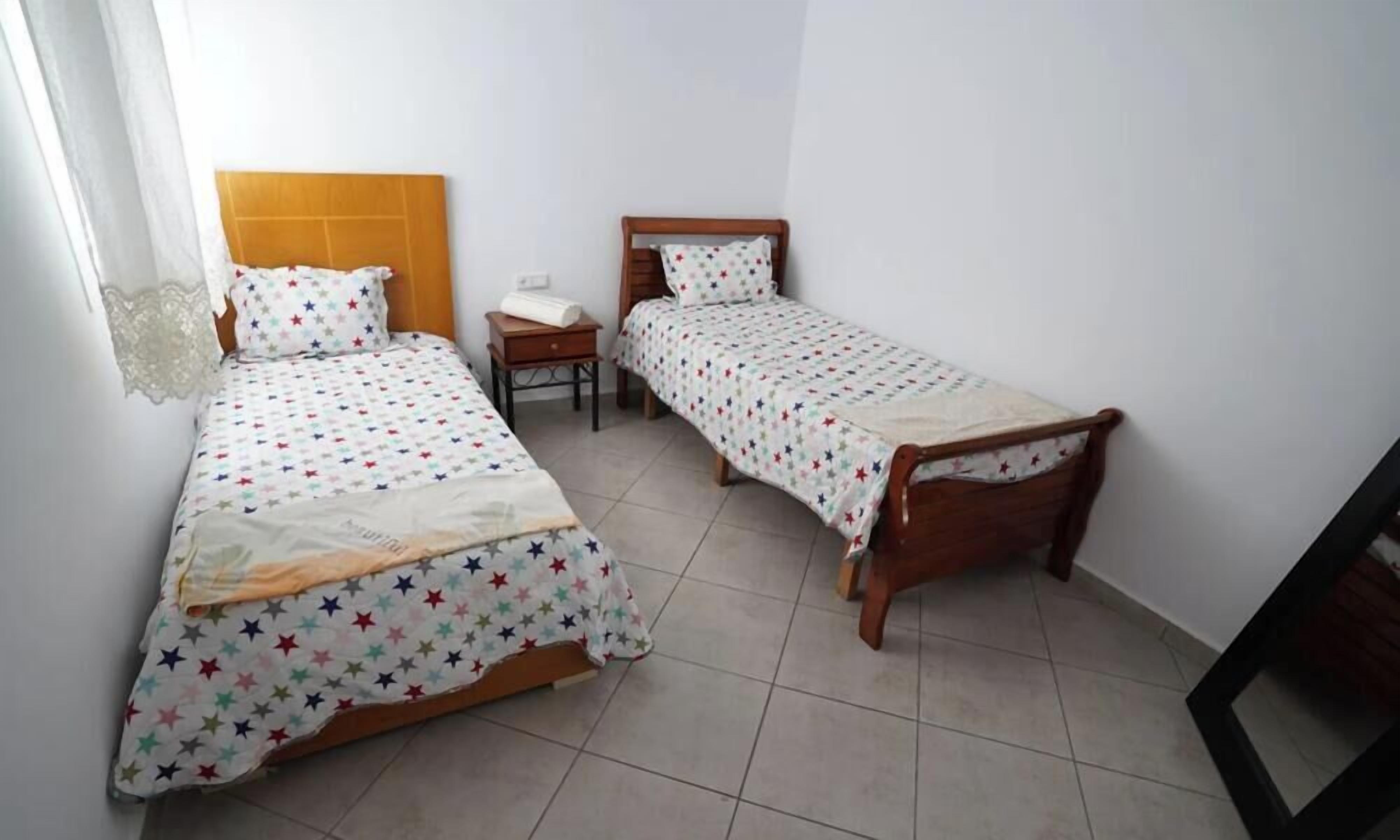 Une chambre avec deux lits simples, une table de chevet et une petite table.