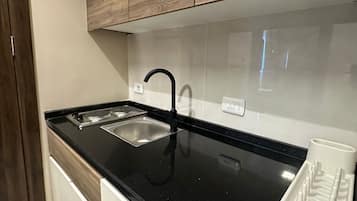 Una cucina moderna con piano di lavoro nero, lavello in acciaio inossidabile e mobili in legno.