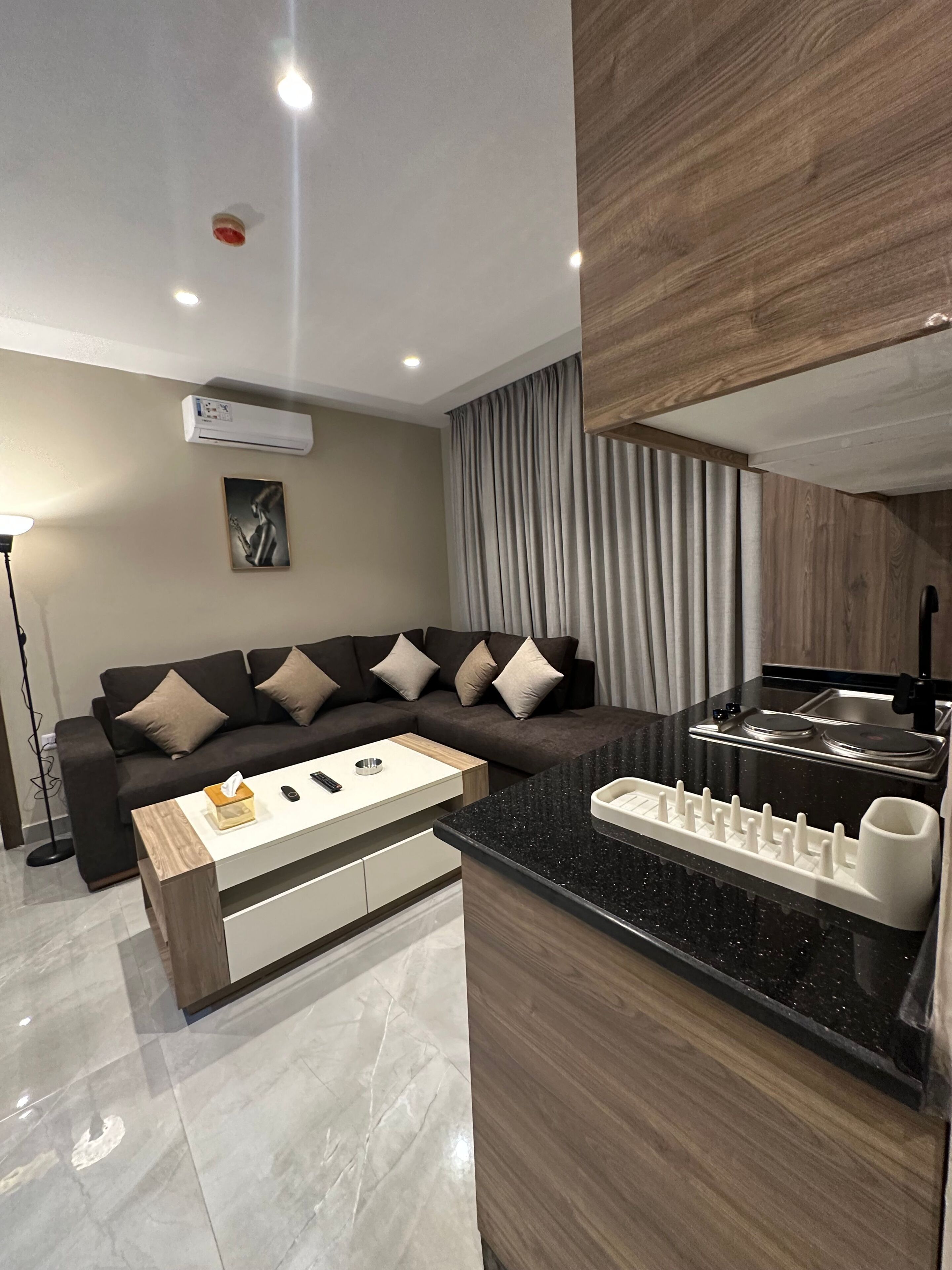Una sala moderna con un sofá, una mesa de centro y una zona de cocina con estufa.
