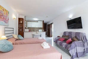 A hotel room with two beds, a sofa, a TV, and a kitchenette. - San Marino 41 - Studio (Los Cristianos)