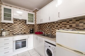A compact kitchen with white cabinetry, a built-in oven, a dishwasher, and a coffee maker. - San Marino 41 - Studio (Los Cristianos)