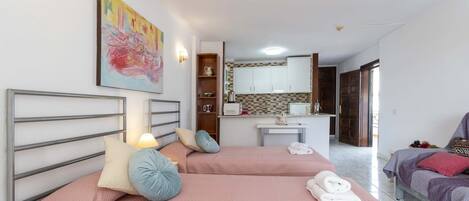Une chambre d’hôtel avec deux lits, une kitchenette et un tableau au mur.