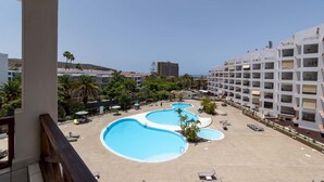 Et hotel med flere swimmingpools, et anlagt område med palmer og havudsigt.