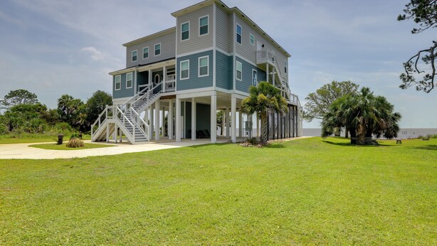A two-story house with a covered porch and a staircase leading to the upper floor. - Waterfront Family Home w/ Views in Carrabelle (Carrabelle)