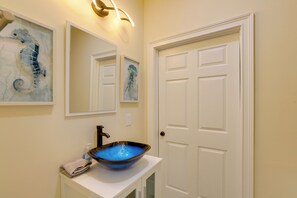 A bathroom with a white sink, a mirror, and a door. - Waterfront Family Home w/ Views in Carrabelle (Carrabelle)
