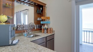 A kitchen with a granite countertop, a stainless steel sink, and a mirror above it. There are decorative items on the shelves and a sign that reads 'Captain's Quarters'. - Waterfront Family Home w/ Views in Carrabelle (Carrabelle)